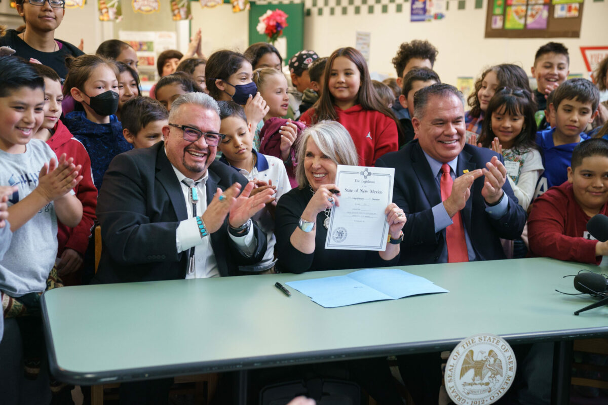 Senator Leo Jaramillo (left), Governor Michelle Lujan Grisham, and Sen. Michael Padilla (right) are joined by students from East San Jose Elementary School in Albuquerque, New Mexico for the singing of Senate Bill 4. The bill will make breakfast and lunch free for all students in New Mexico, regardless of their family’s ability to pay.