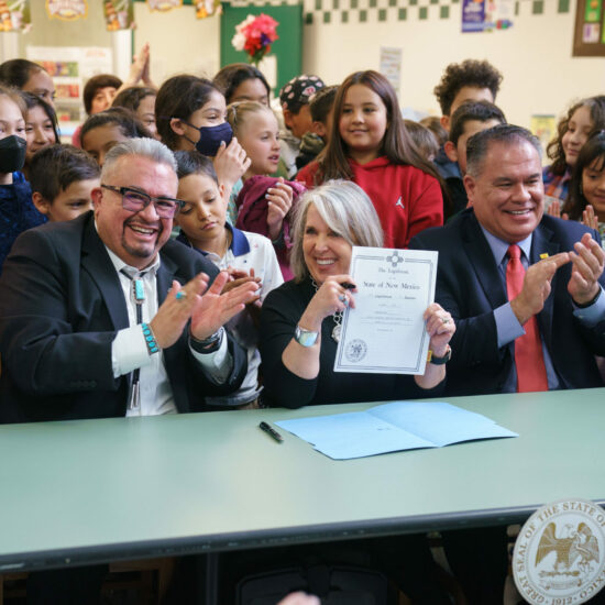 Senator Leo Jaramillo (left), Governor Michelle Lujan Grisham, and Sen. Michael Padilla (right) are joined by students from East San Jose Elementary School in Albuquerque, New Mexico for the singing of Senate Bill 4. The bill will make breakfast and lunch free for all students in New Mexico, regardless of their family’s ability to pay.