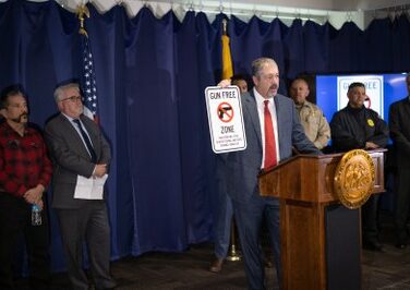 Bernalillo County District Attorney Sam Bregman, holding a “Gun Free Zone” sign, was joined by leaders from the US Department of Justice, law enforcement officials from across the county, and Albuquerque Public School Superintendent Scott Elder to remind parents and students that bringing a firearm onto school property is a crime.