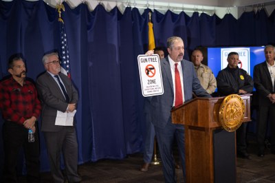 Bernalillo County District Attorney Sam Bregman, holding a “Gun Free Zone” sign, was joined by leaders from the US Department of Justice, law enforcement officials from across the county, and Albuquerque Public School Superintendent Scott Elder to remind parents and students that bringing a firearm onto school property is a crime.