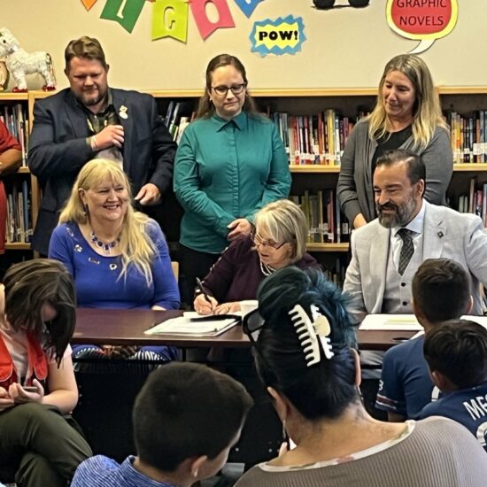Representative Elizabeth Thomson (left), Governor Michelle Lujan Grisham, and Public Education Secretary Arsenio Romero (right) celebrated the signing of an executive order establishing the Office of Special Education in the Public Education Department while surrounded by parents and children in the library of Lowell Elementary School on May 25.