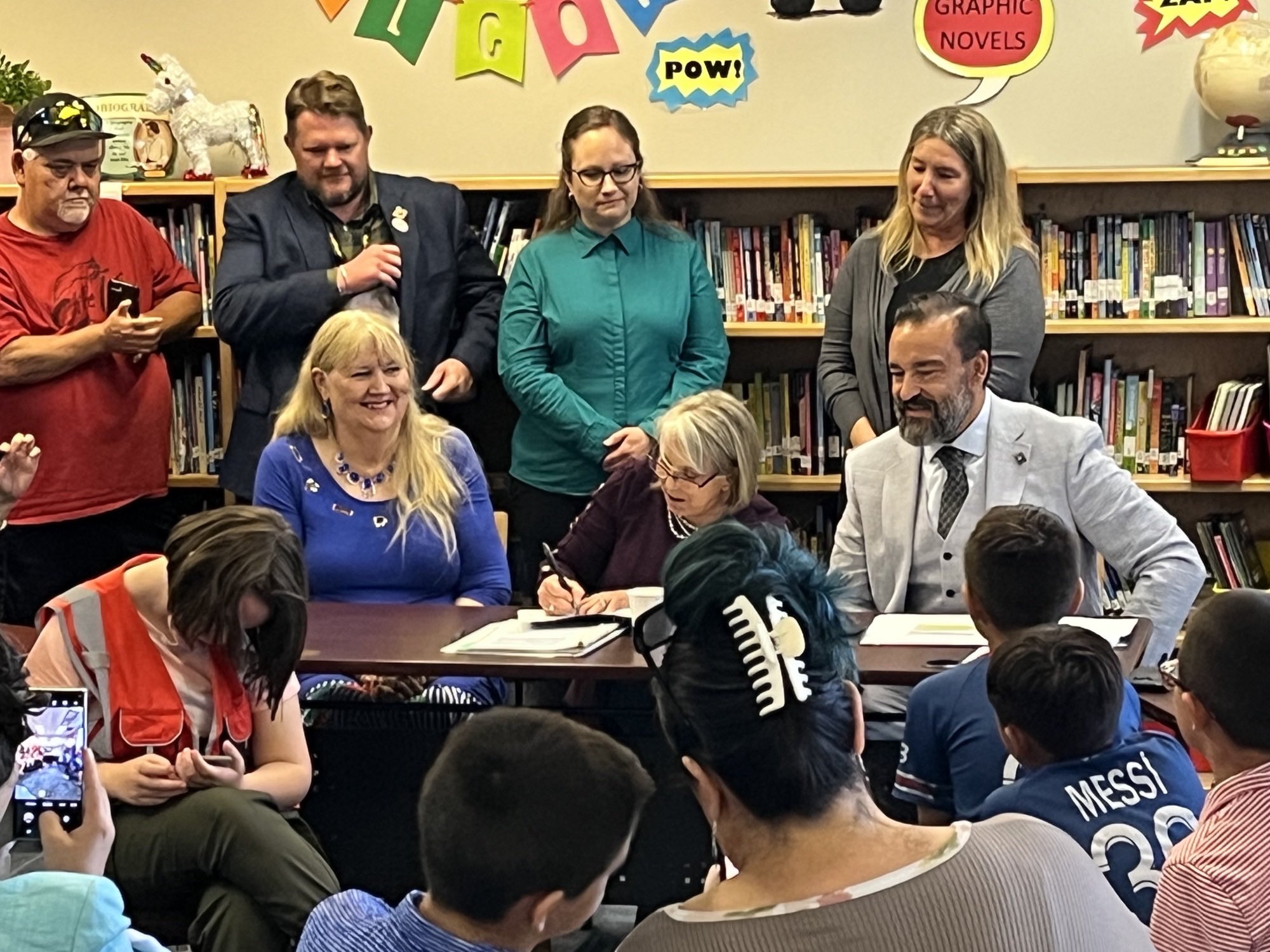 Representative Elizabeth Thomson (left), Governor Michelle Lujan Grisham, and Public Education Secretary Arsenio Romero (right) celebrated the signing of an executive order establishing the Office of Special Education in the Public Education Department while surrounded by parents and children in the library of Lowell Elementary School on May 25.